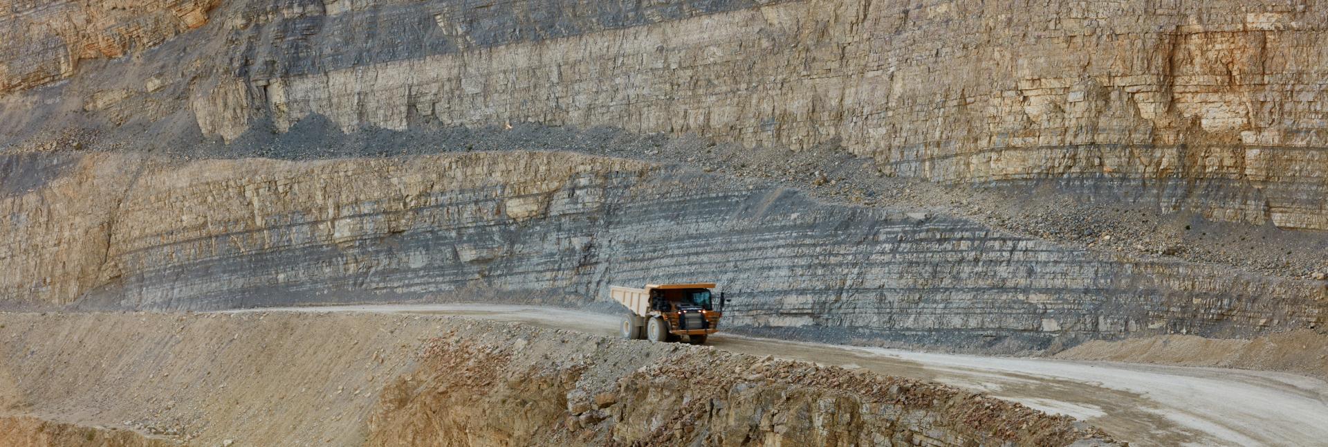 Ein gelber Dumper fährt durch einen Steinbruch.
