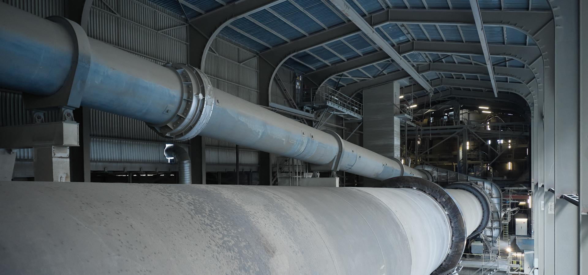 Das Dach einer Fabrikhalle mit grossen Stahlröhren, die horizontal durchlaufen.