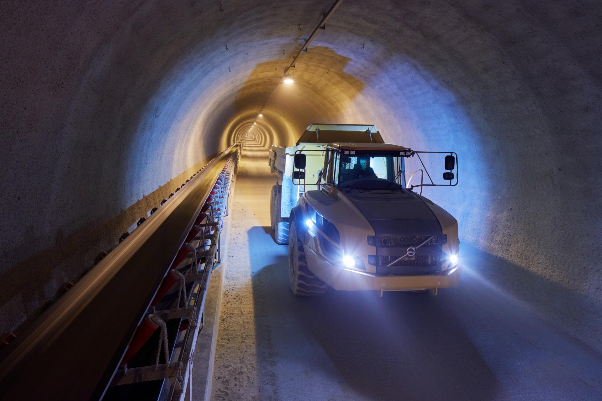 Ein Bagger fährt durch einen runden betonverkleideten Tunnel